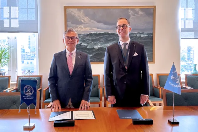 Professor Maximo Q. Mejia, Jr. and Professor Henrik Wenander standing in front of desk after signing the memorandum of understanding. Photo.