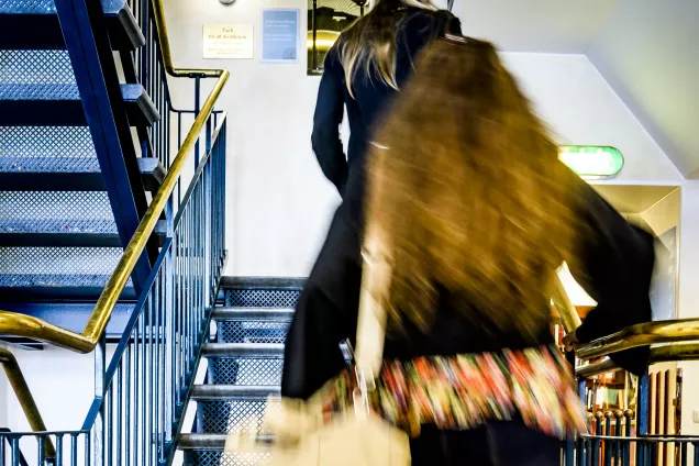 Bild av student som går i trappan i Juridiska fakultetens bibliotek. Foto.