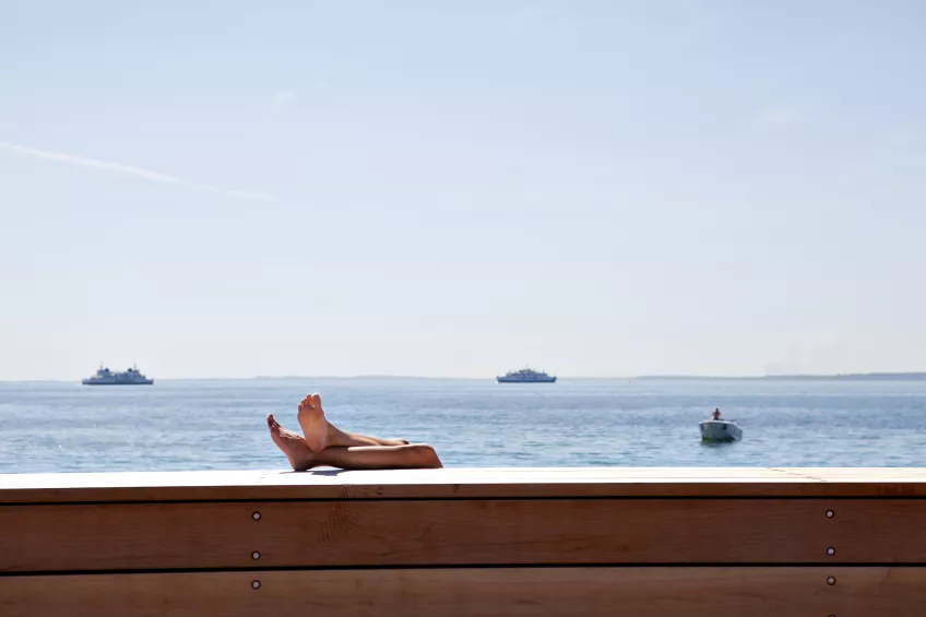 A sunny summer's day by the ocean with boats in the background. 
