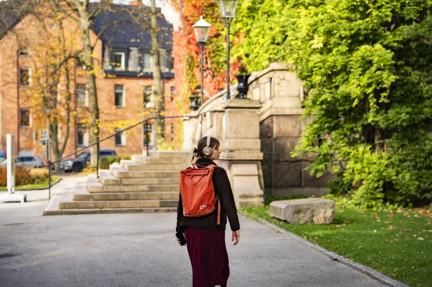 A girl with a backpack, curiously exploring the lush streets of Lund. Photo.